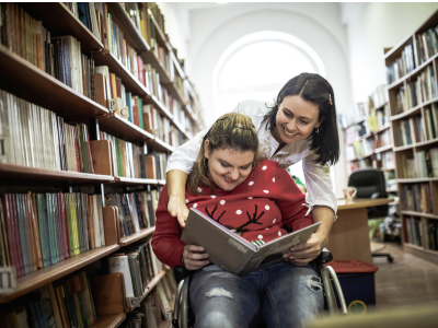 Highschool student who uses a wheelchair in the library with her mother.