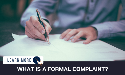 Image of a man’s hands signing a document with a pen. Below the image is a black box with white text reading “WHAT IS A FORMAL COMPLAINT?”. To the left is a white box with dark blue text reading “LEARN MORE” with and orange and blue cursor icon graphic to the right.